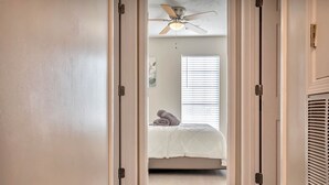Un dormitorio con cama, ventilador de techo y ventana con persianas.
