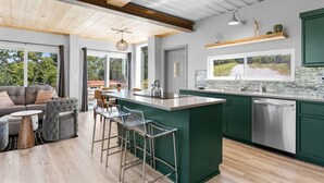 A modern kitchen with a central island, bar stools, and a view of the outdoors.