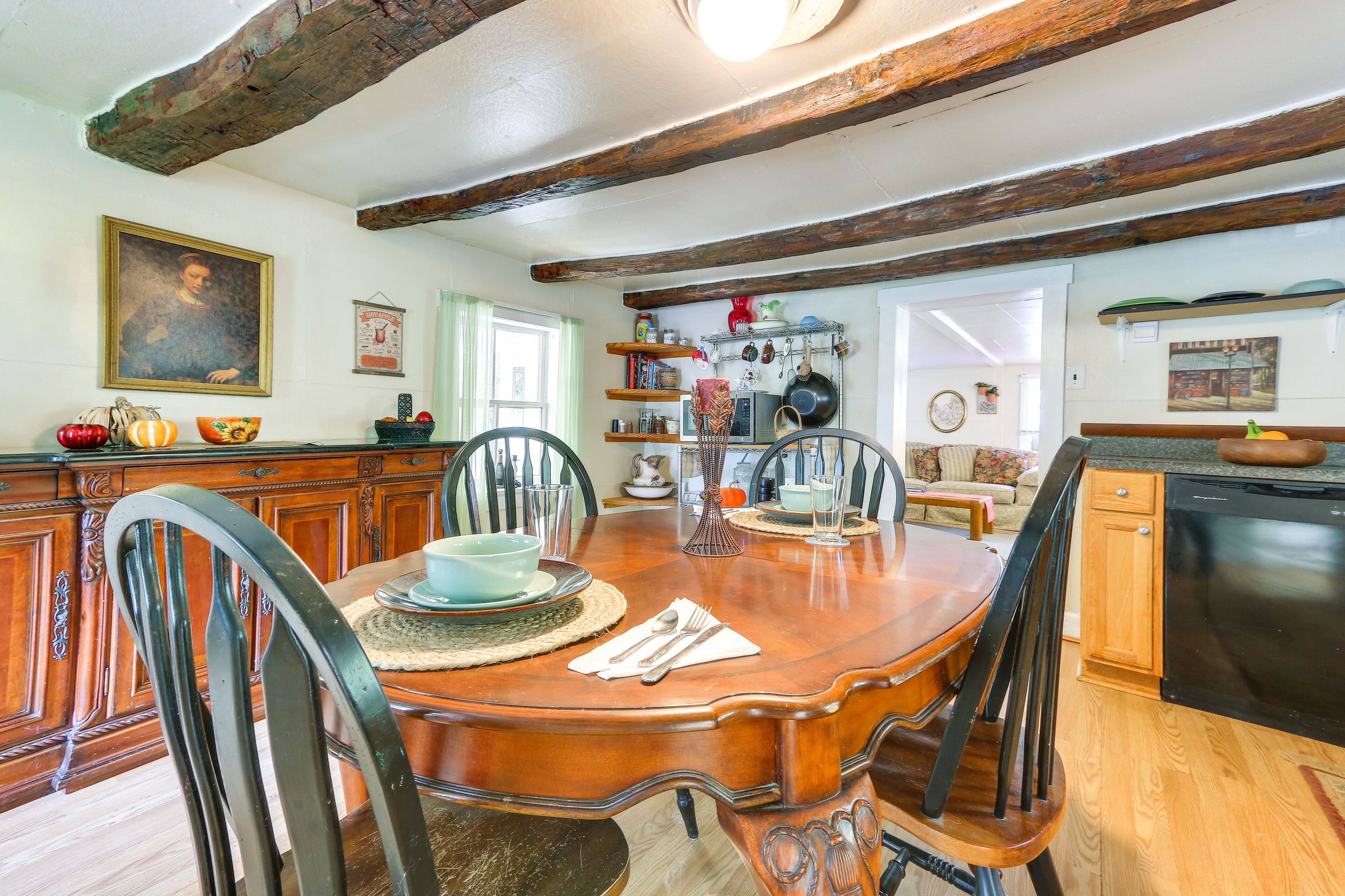 A dining area with a wooden table, chairs, and a kitchen in the background.