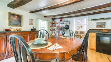 A dining area with a wooden table, chairs, and a kitchen in the background.
