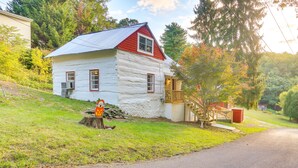 Eine Blockhütte mit rotem Dach und weißen Wänden, einer Holzterrasse und einer Treppe, die zu einer Veranda führt.