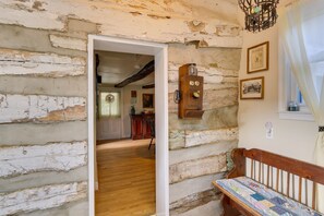 A rustic room with exposed brick walls, a wooden bench, and a door leading to another room. - Historic Boonsboro Vacation Rental w/ Grill (Boonsboro)