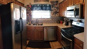A compact kitchen with a refrigerator, sink, dishwasher, stove, and microwave. - Family-sized home with quick access to the loop!! (Midland)