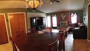 A spacious dining area with a large wooden table and chairs, a television, and a fireplace in the background. - Family-sized home with quick access to the loop!! (Midland)