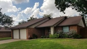 A two-story brick house with a garage, a front porch, and a well-maintained lawn. - Family-sized home with quick access to the loop!! (Midland)