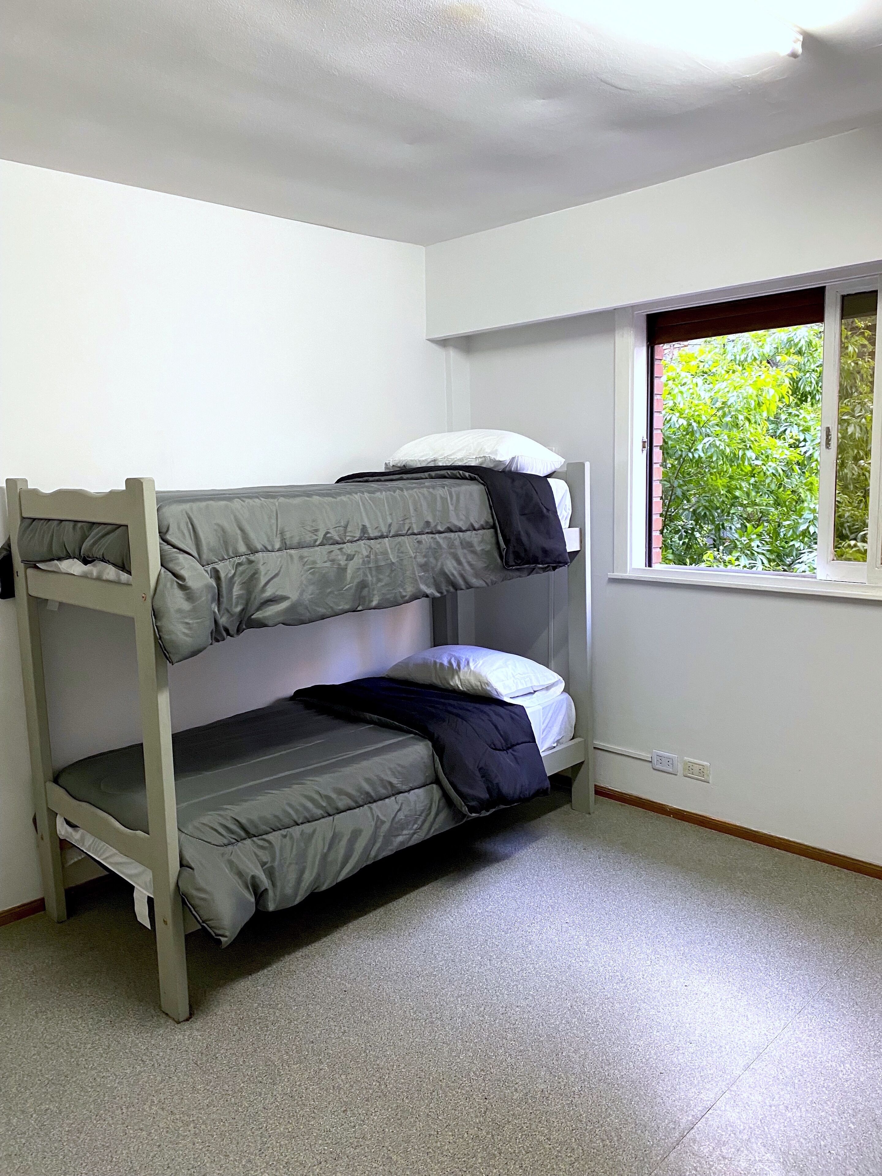 A bunk bed in a room with white walls and a window.