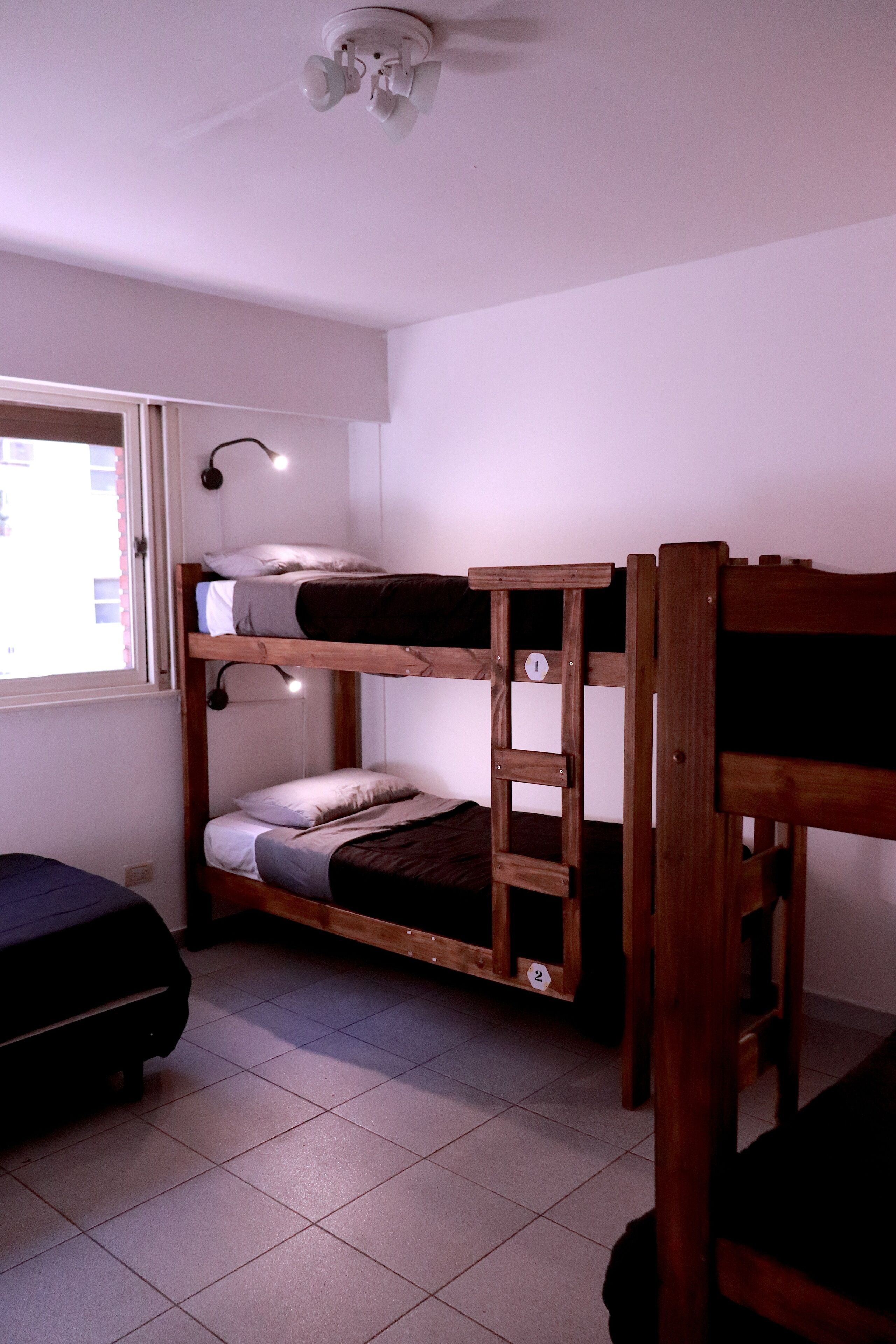 A bunk bed room with a window, a desk, and a ceiling fan.