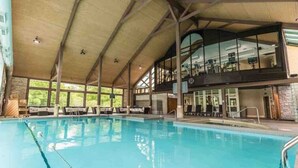 A large indoor swimming pool with a high ceiling and a second level balcony overlooking the pool.