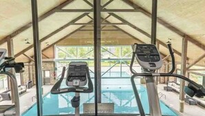 An indoor gym with exercise equipment and a view of an outdoor swimming pool.