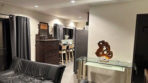 Un salon moderne avec un canapé en cuir, une table basse en verre et un coin repas comprenant des chaises et une table.