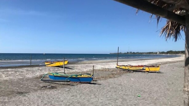 Une plage avec plusieurs bateaux sur le sable et l’océan en arrière-plan.