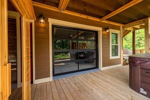 Eine Holzdielen-Terrasse mit einer Schiebeglastür zu einem überdachten Bereich.