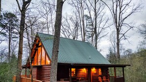 A log cabin with a porch and deck, surrounded by trees. - Happily Ever After (Gatlinburg)
