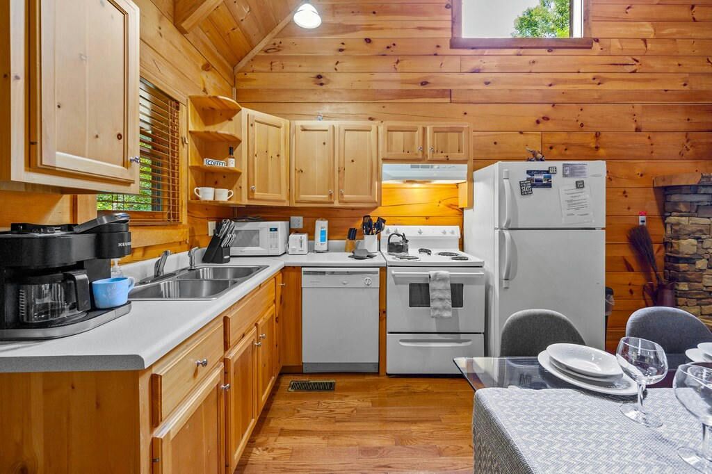 A compact kitchen with wooden cabinets, a white refrigerator, a stove, and a sink.