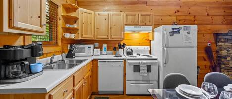 A compact kitchen with wooden cabinets, a white refrigerator, a stove, and a sink.