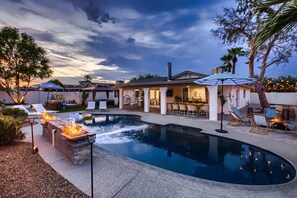Un patio trasero con piscina, mobiliario exterior y zona de barbacoa.