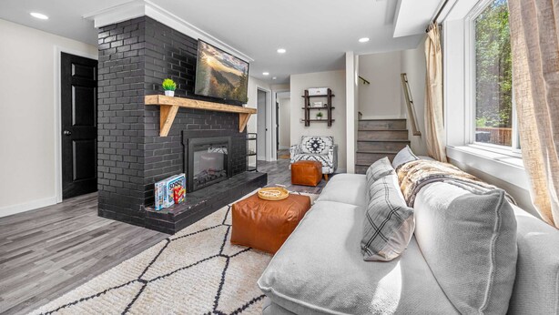 Una sala moderna con chimenea, un sofá y una escalera que lleva a otro nivel.