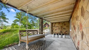 Un espacio de estar al aire libre techado con una silla mecedora, un tapete estampado y paredes de piedra.
