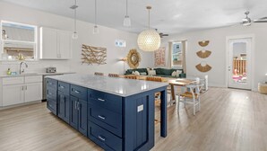 A spacious kitchen with a large island, white cabinets, and a dining area with a wooden table and chairs. - 6-Min Walk to Beach | Heated Pool | Fenced Yard (Panama City)