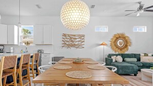 A modern kitchen with white cabinets, a wooden dining table with placemats, and a ceiling fan. - 6-Min Walk to Beach | Heated Pool | Fenced Yard (Panama City)
