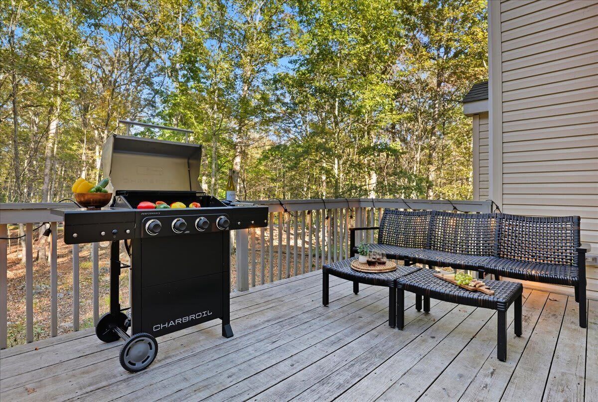 Een barbecue op een houten terras, met een bankje en een bloempot in de buurt.