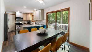 A modern kitchen with a dining area, featuring a large island, built-in appliances, and a view to the outdoors. - 5BR|Private Lake|Pools|Hot Tub|Near Camelback (East Stroudsburg)