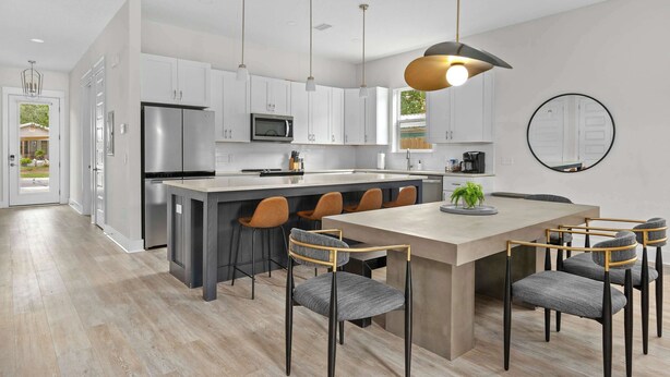 A modern kitchen with white cabinets, stainless steel appliances, and a central island with bar stools. - Steps to Beach, Free Heated Pool & Fire Pit! (Panama City Beach)