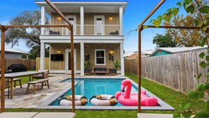 A two-story house with a backyard pool, outdoor seating, and a wooden fence. - Steps to Beach, Free Heated Pool & Fire Pit! (Panama City Beach)