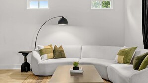 A modern living room with a light grey sofa, a small side table, a floor lamp, and a coffee table with a plant and books. - Steps to Beach, Free Heated Pool & Fire Pit! (Panama City Beach)