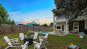 Un jardin avec une terrasse en bois, un espace salon extérieur et une piscine.