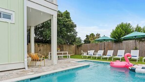 Un jardin avec une piscine, des chaises longues et une clôture en bois.