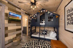 Ein gemütliches Zimmer mit Etagenbett, Deckenventilator, einem gerahmten Bild an der Wand und Teppichboden.