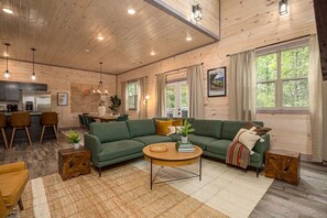 Ein gemütliches Blockhaus-Interieur mit einem grünen Sofa, Holzelementen und einem Essbereich.