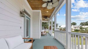 A covered porch with a wooden bench, a white sofa, and a table. - Private Pool | Near MarshWalk & Beach | Fire Pit (Murrells Inlet)