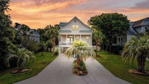 A two-story house with a front porch, surrounded by palm trees and a well-maintained lawn. - Private Pool | Near MarshWalk & Beach | Fire Pit (Murrells Inlet)