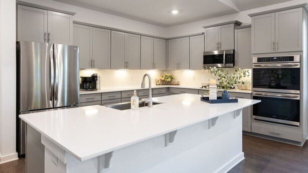 Una cocina moderna con electrodomésticos de acero inoxidable, una isla central y armarios de color gris claro.