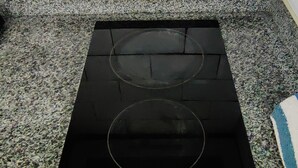 Ein schwarzer Induktionskochfelds mit zwei Kochzonen und einer Bedienfeld mit Tasten.