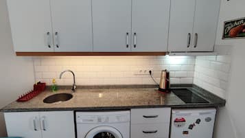 Een koelkast, een oven, een broodrooster, kookgerei, borden en bestek