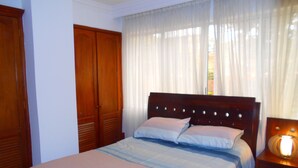 Une chambre à coucher avec un lit, une armoire en bois et une table de chevet avec une lampe.