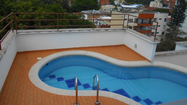Une piscine sur le toit offrant une vue sur le paysage urbain et les montagnes en arrière-plan.