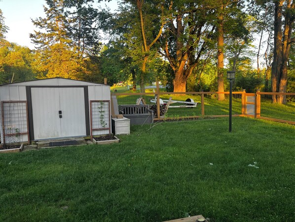 A fenced yard with a shed, a birdhouse, and a tree. - COZY LAKE COTTAGE/CASITA in a quaint country setting (Reading)