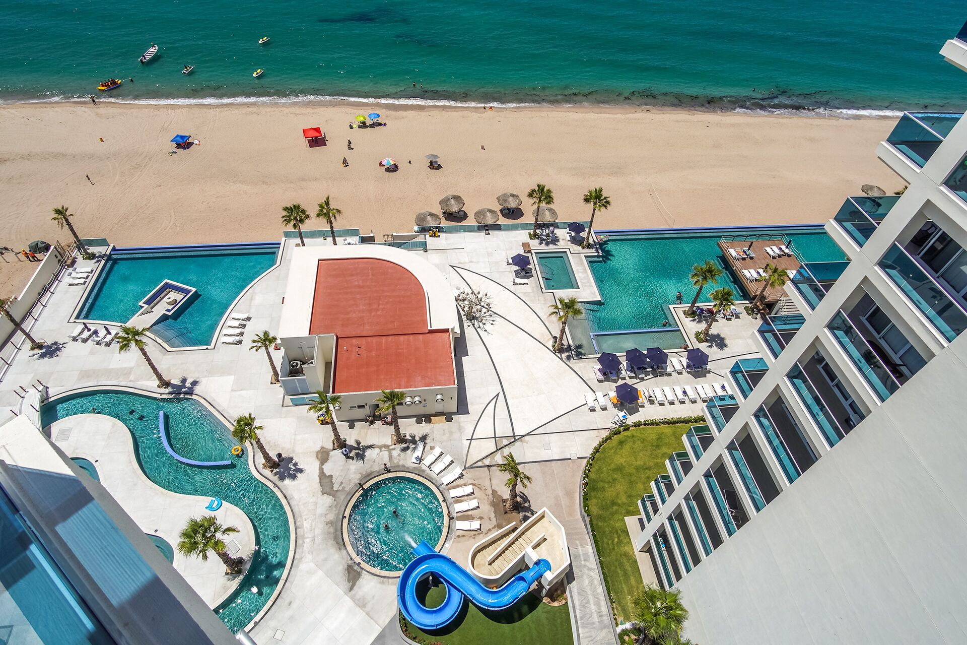 Un resort con varias piscinas, una playa y un tobogán de agua.