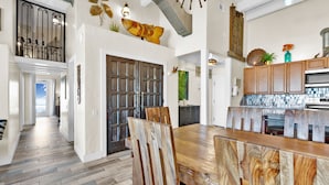 A spacious kitchen with a wooden dining table, a built-in oven, and a variety of decorative items on the walls. - Penthouse Dahktari is a true beach front high-rise (10th floor) condominium (South Padre Island)