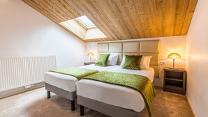 Ein Schlafzimmer mit zwei Betten, einem Oberlicht, einer Heizung und Nachttischlampen.