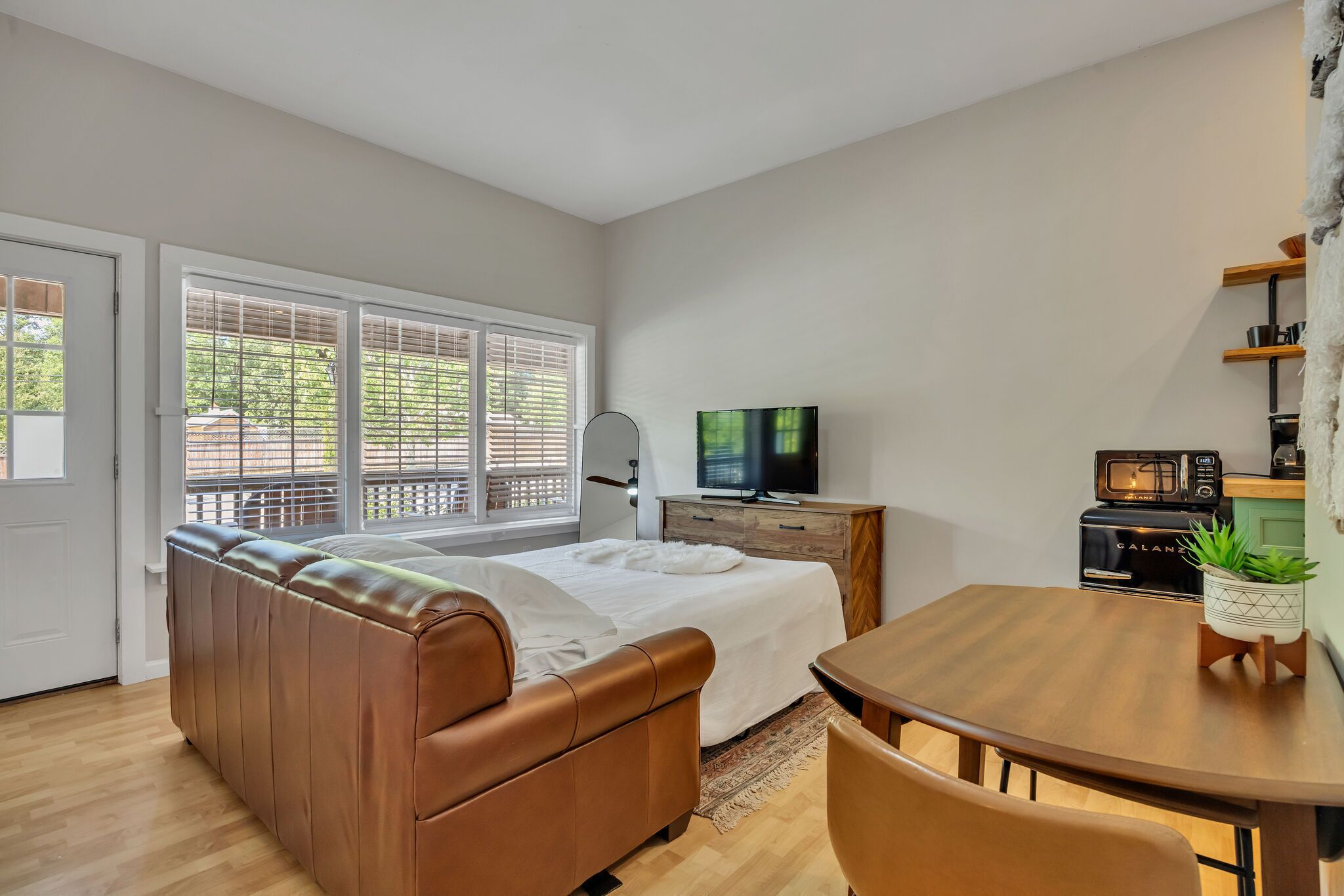 Une chambre moderne équipée d’un lit, d’une télévision, d’une table à manger et d’un coin cuisine.