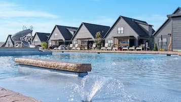 En swimmingpool med stenkant, omgivet af huse med skrå tage og en klar himmel.