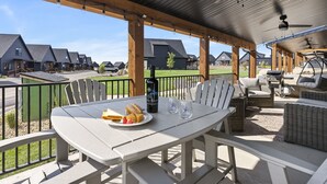 An outdoor patio with a table set for dining, surrounded by wicker furniture and a view of residential buildings.