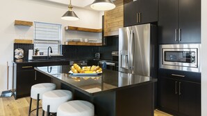 A modern kitchen with a central island, stainless steel appliances, and black cabinetry.
