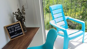 Un balcón con una silla azul y un estante de madera con un cartel de bienvenida.