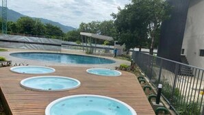 Un área de piscina con una piscina grande central y tres jacuzzis más pequeños en un muelle de madera.